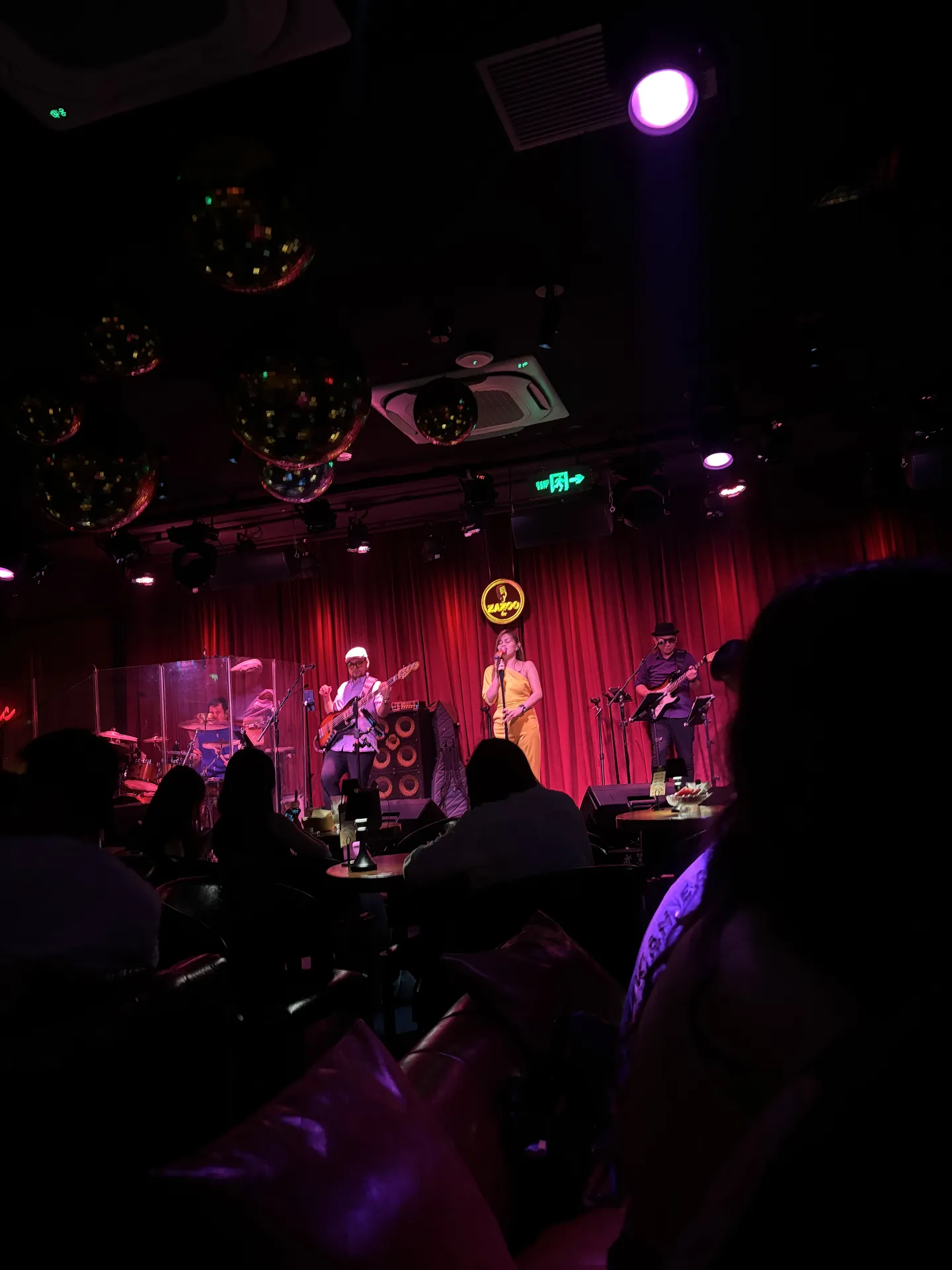 A band playing on a stage with a red curtain in a dark bar