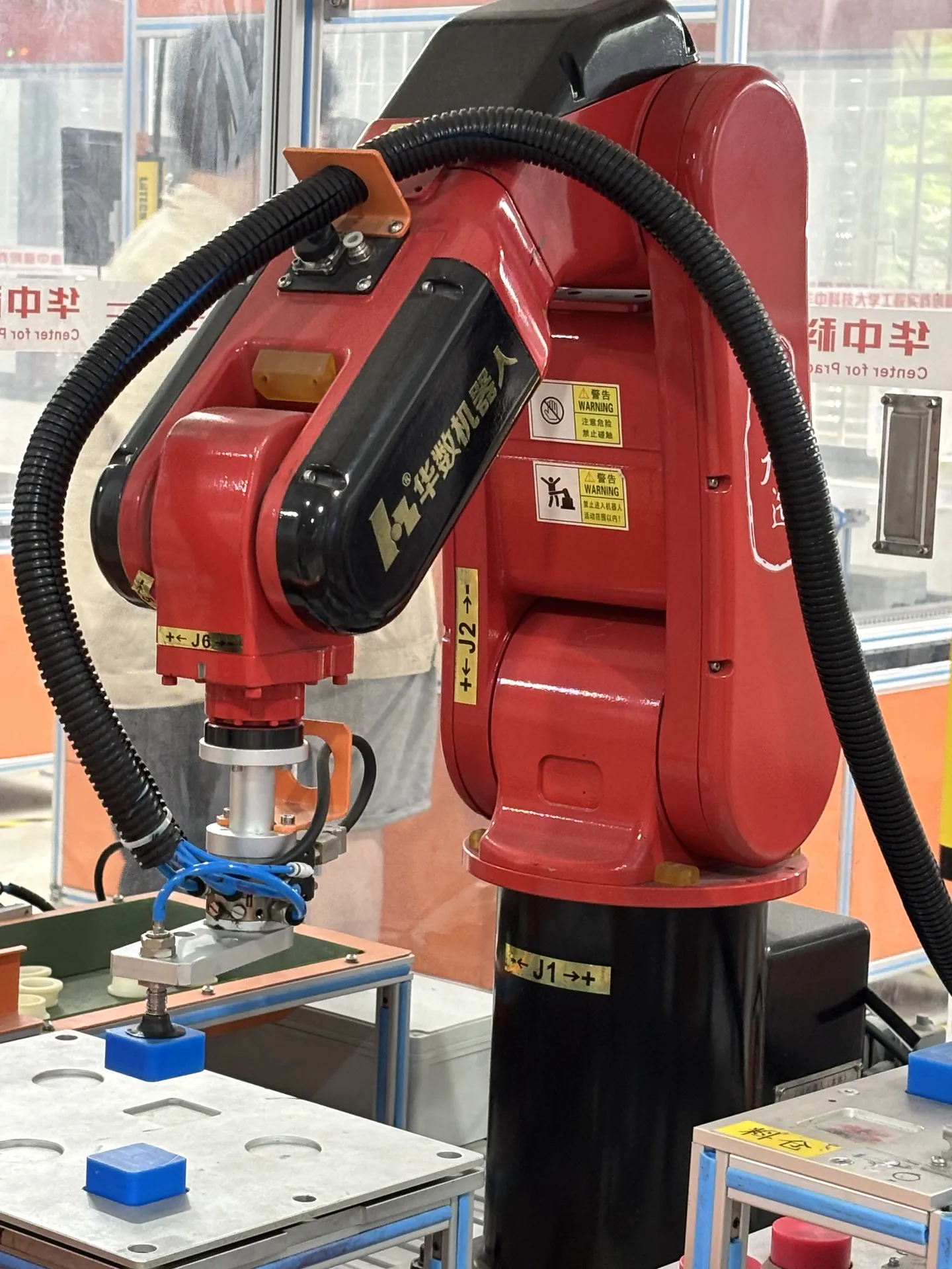 A red industrial robot arm with a suction gripper above a pick and place station