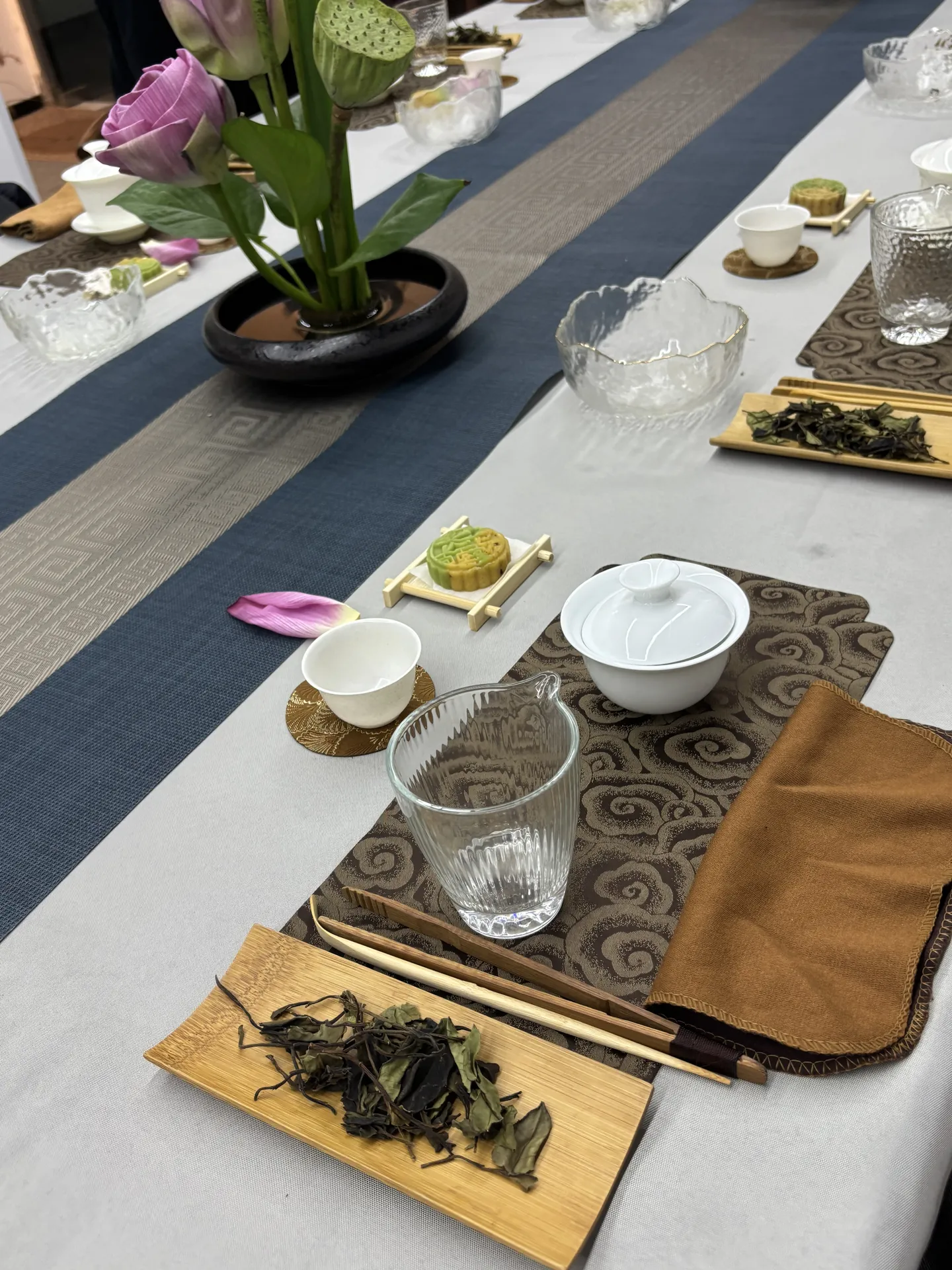 A table set for a tea ceremony with tea leaves, a gaiwan, cups and mooncakes